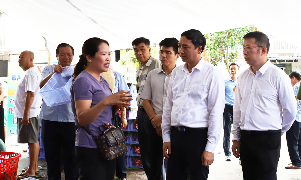 Đồng chí Nguyễn Việt Oanh trao đổi với thương nhân thu mua vải thiều tại điểm cân ở xã Giáp Sơn.